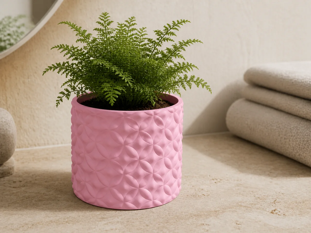 Pink braided-weave planter holding a fern beside folded towels